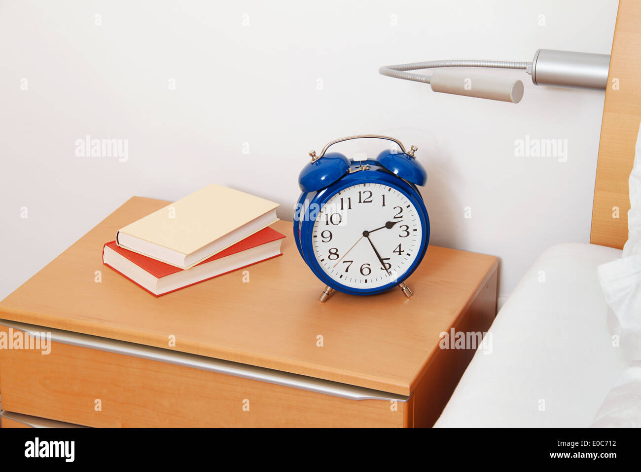 An alarm clock and a book in a bedroom, Ein Wecker und ein Buch in einem Schlafzimmer Stock Photo