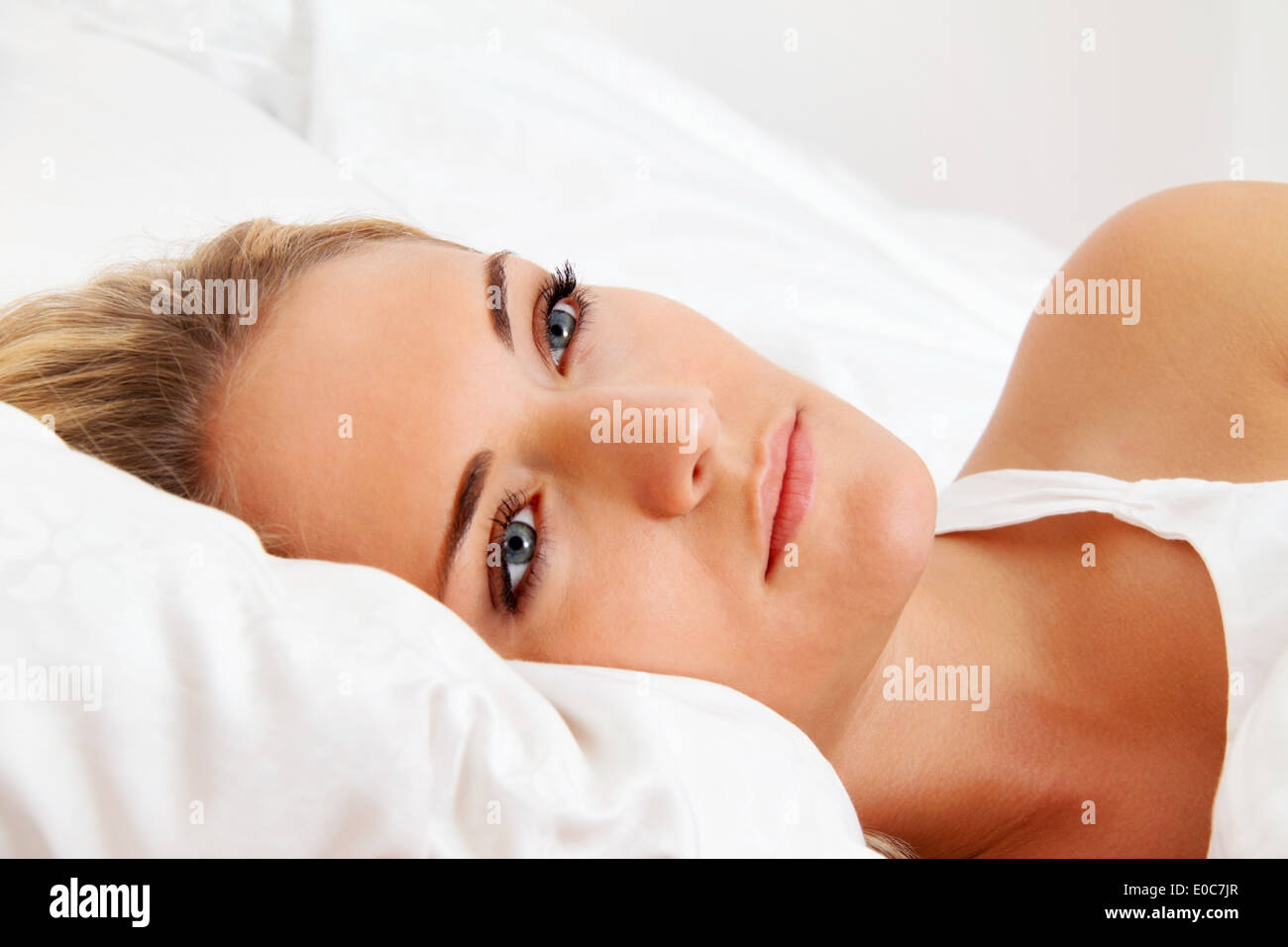 A young woman lies awake in the bed. Sleepless and thoughtfully., Eine junge Frau liegt wach im Bett. Schlaflos und nachdenklich Stock Photo