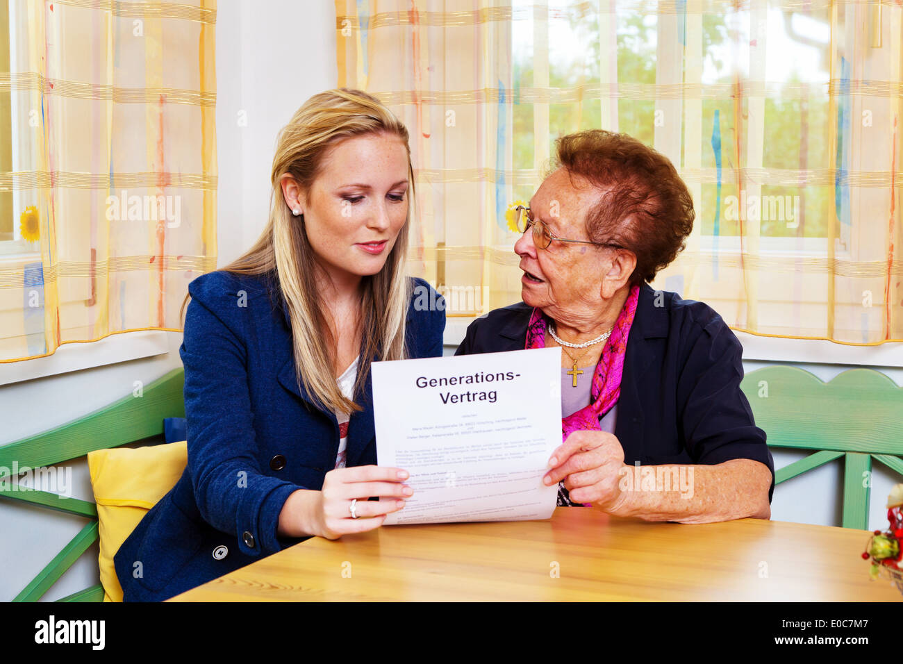 A grandson visits his grandmother and reads a generation contract., Ein Enkel besucht seine Grossmutter und liest einen Generati Stock Photo