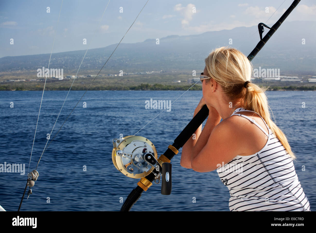 A woman lost in her thoughts watches the shore of Kona, Hawaii in the distance Stock Photo