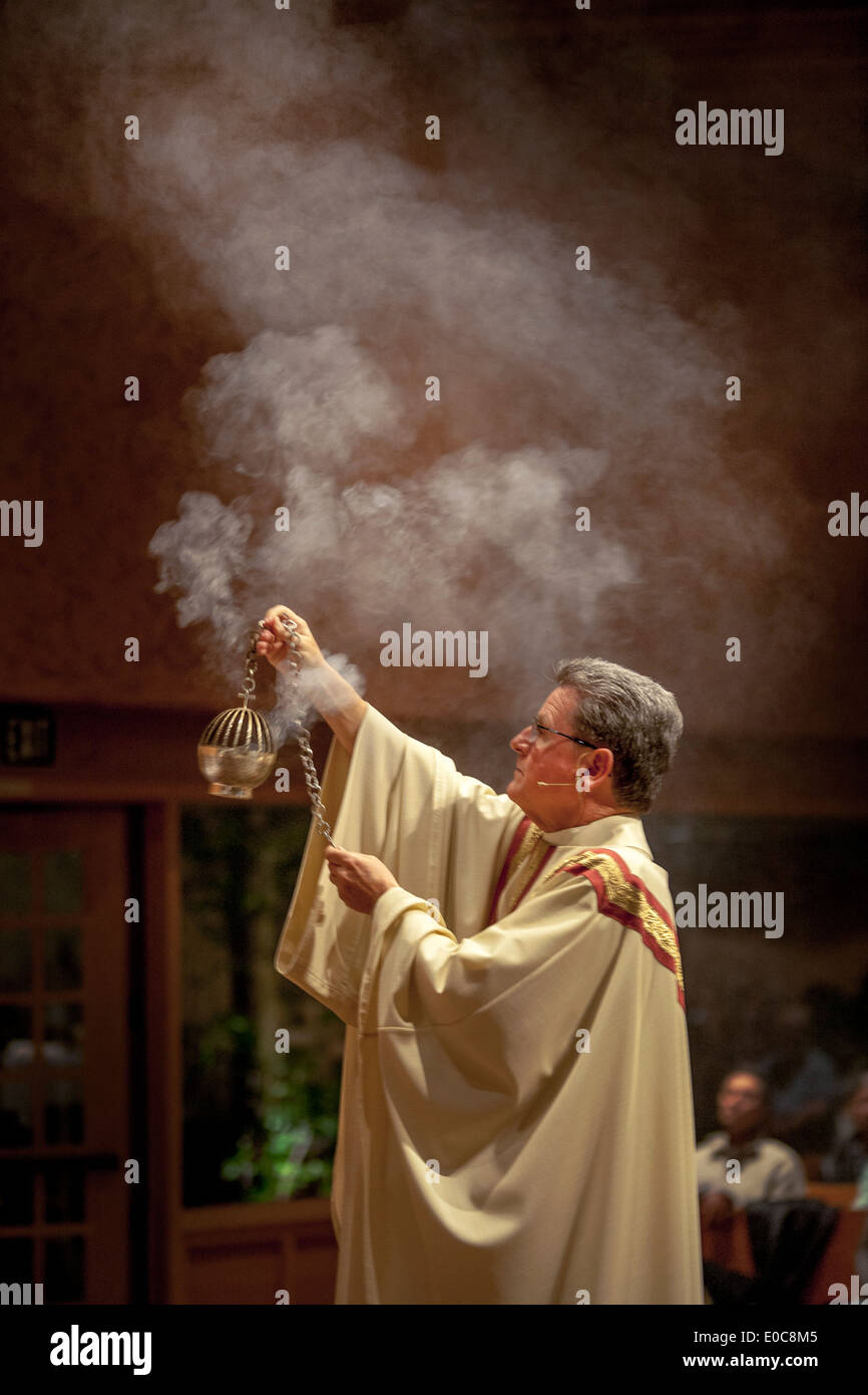 During the Great Easter Vigil mass at St. Timothy's Catholic Church, Laguna Niguel, CA, the pastor waves a censer (incense burner) signifying prayers rising with the smoke. Stock Photo