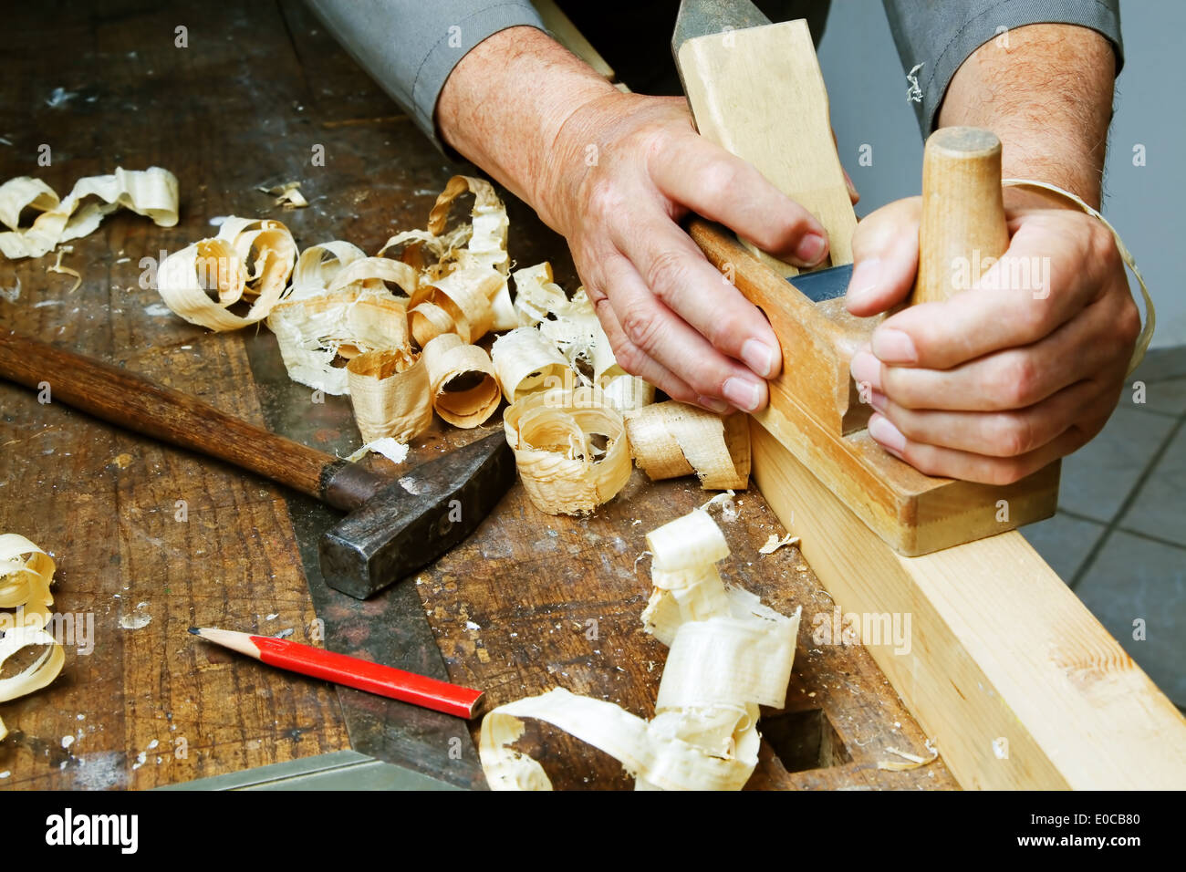 A joiner with a plane and wood shavings in the workshop., Ein Tischler mit einem Hobel und Holzspaenen in der Werkstatt. Stock Photo