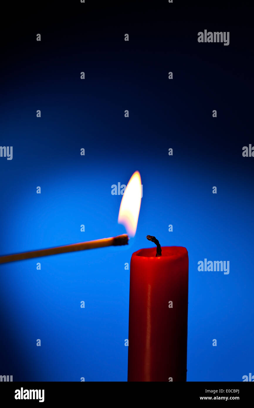 A red candle is lighted with a match., Eine rote Kerze wird mit einem  Streichholz angezuendet Stock Photo - Alamy