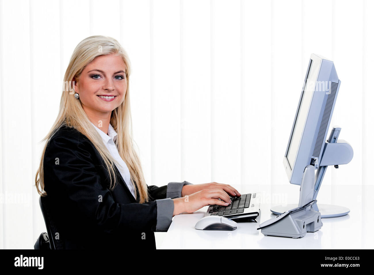 Young woman sits before a computer in the office., Junge Frau sitzt vor einem Computer im Buero. Stock Photo