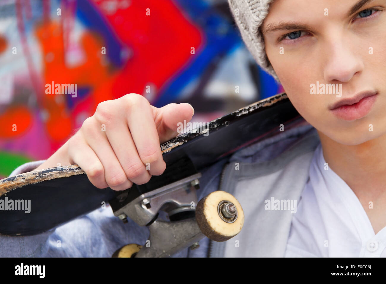 A cool looking youthful man before graffiti, Ein cool blickender Jugendlicher Mann vor Graffiti Stock Photo