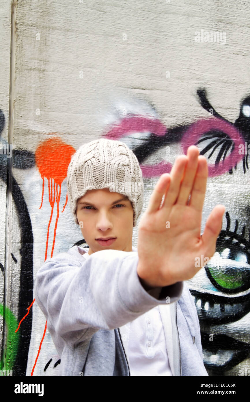 A cool looking youthful man before graffiti, Ein cool blickender Jugendlicher Mann vor Graffiti Stock Photo