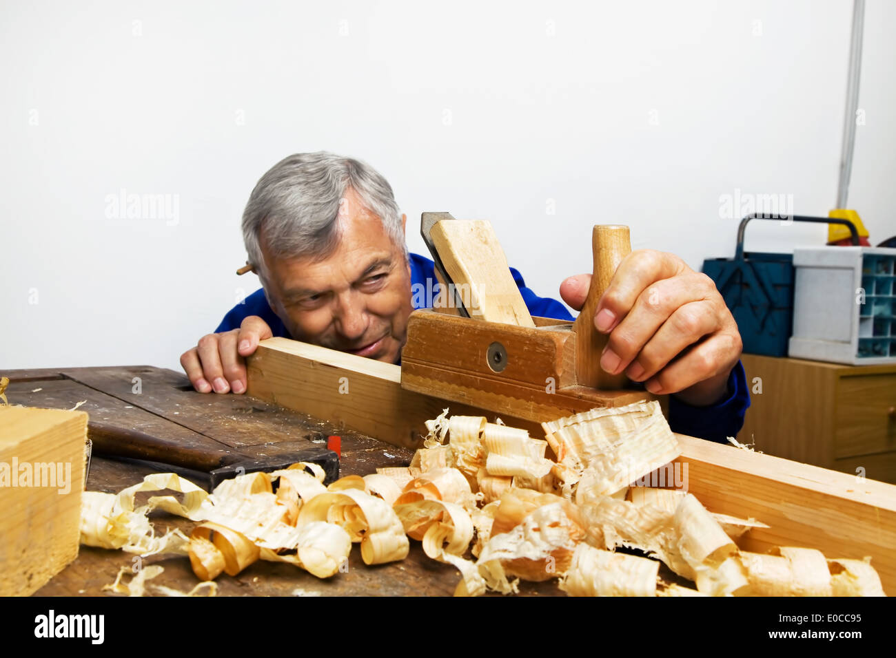 A joiner with a plane and wood shavings in the workshop., Ein Tischler mit einem Hobel und Holzspaenen in der Werkstatt. Stock Photo
