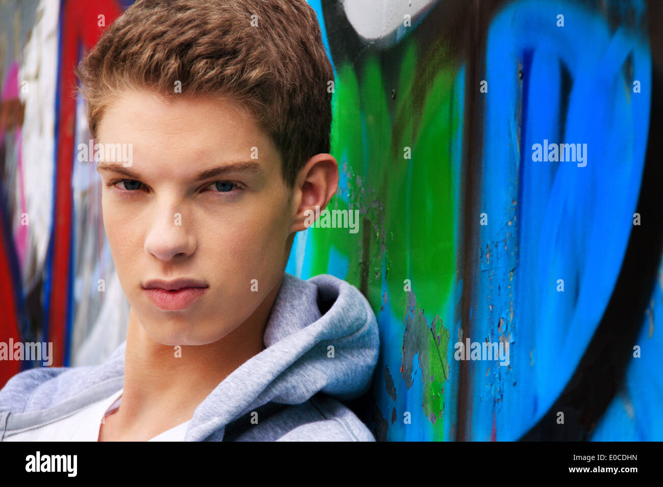A cool looking youthful man before graffiti, Ein cool blickender Jugendlicher Mann vor Graffiti Stock Photo