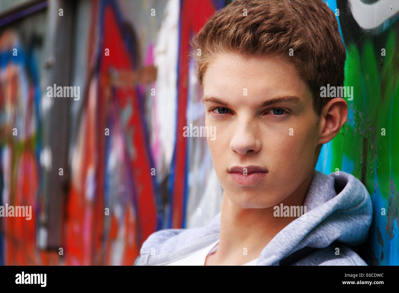 A cool looking youthful man infront of graffiti, Ein cool blickender Jugendlicher Mann vor Graffiti Stock Photo