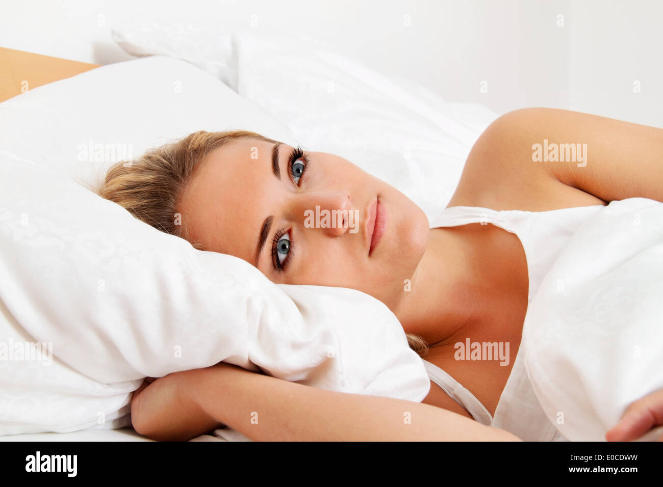 A young woman lies awake in the bed Stock Photo