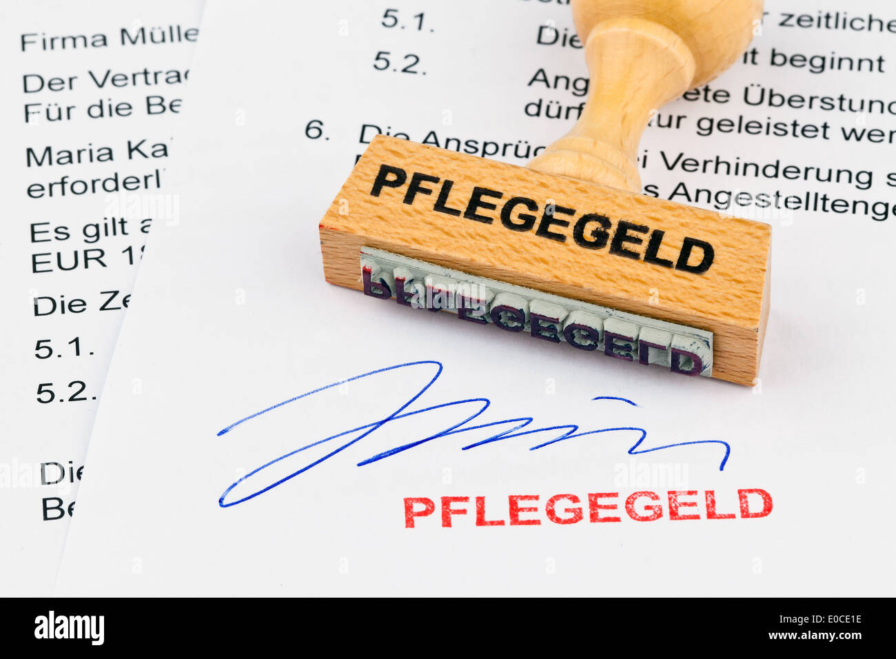 A stamp of wood lies on a document. Label nursing money, Ein Stempel aus Holz liegt auf einem Dokument. Aufschrift Pflegegeld Stock Photo