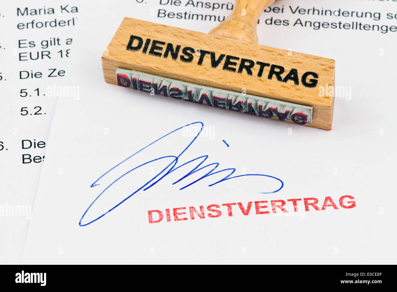 A stamp of wood lies on a document. Label Contract of employment, Ein Stempel aus Holz liegt auf einem Dokument. Aufschrift Dien Stock Photo