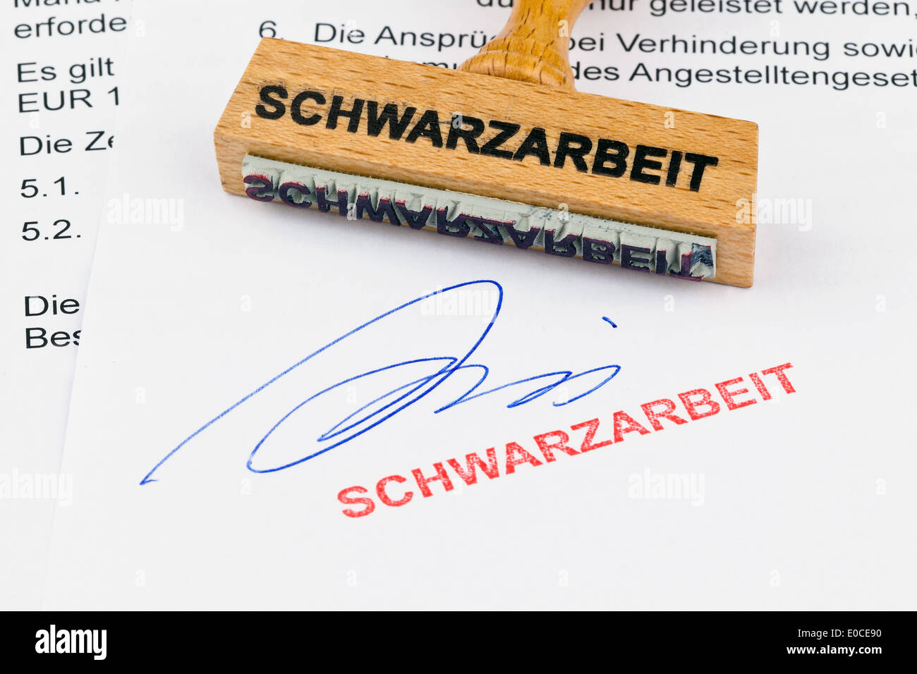A stamp of wood lies on a document. Label Illegal employment, Ein Stempel aus Holz liegt auf einem Dokument. Aufschrift Schwarza Stock Photo