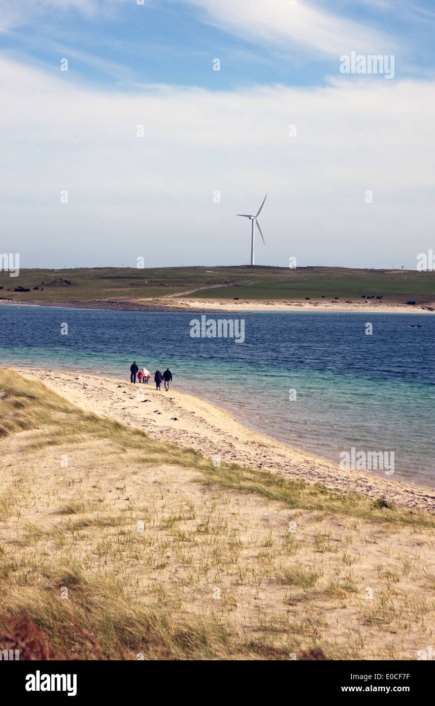 People on the beach on the Orkney island of Glims Holm toward the island of Burray. The Churchill barriers join these islands. Stock Photo