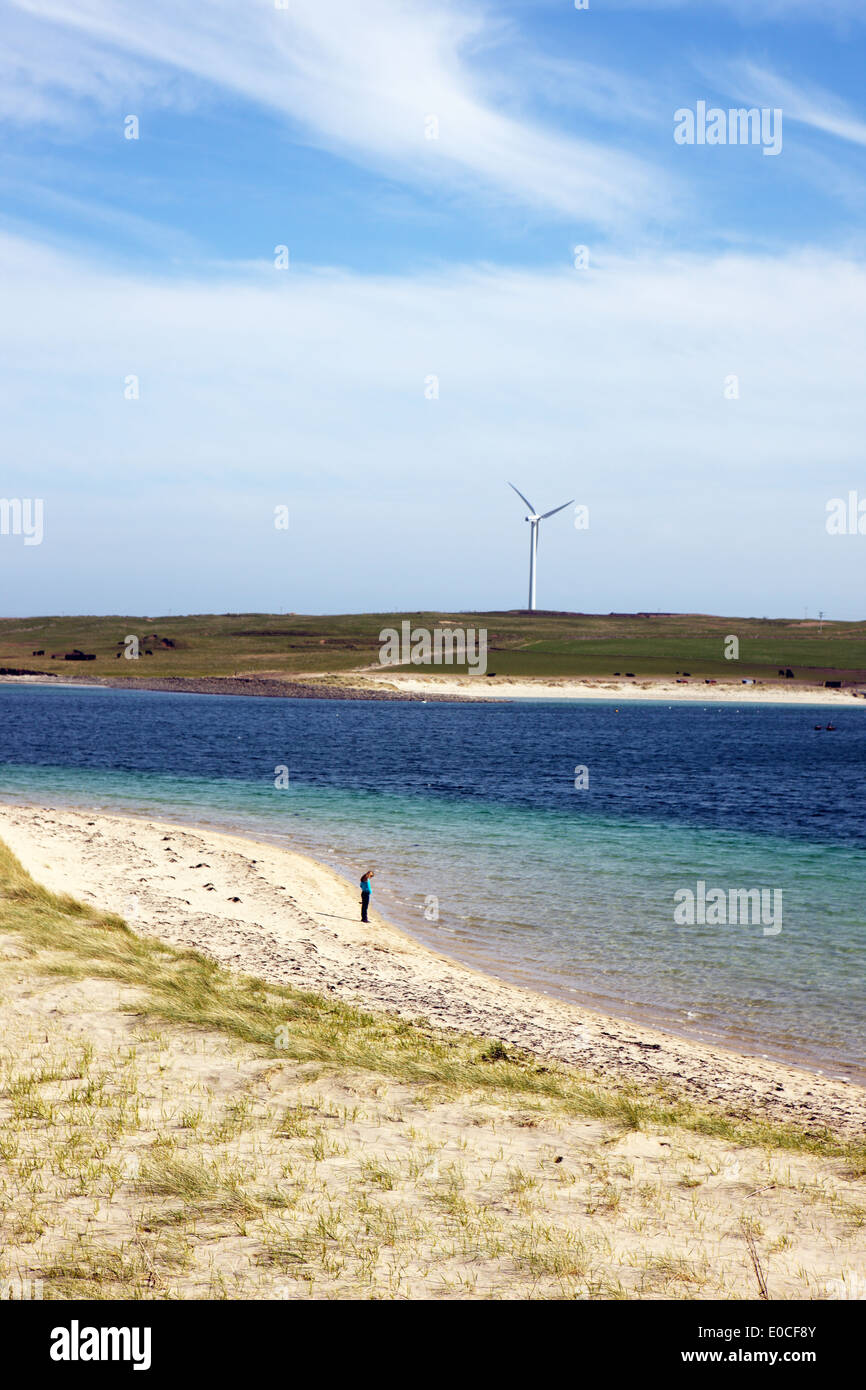 People on the beach on the Orkney island of Glims Holm toward the island of Burray. The Churchill barriers join these islands. Stock Photo