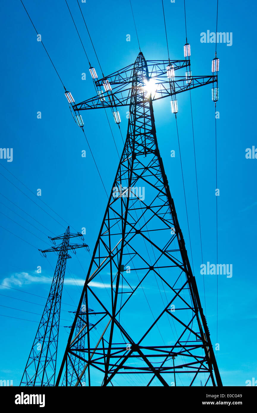 The stream mast of a high-tension management with the sun and blue sky. Energy supply by power supply line., Der Strommast einer Stock Photo