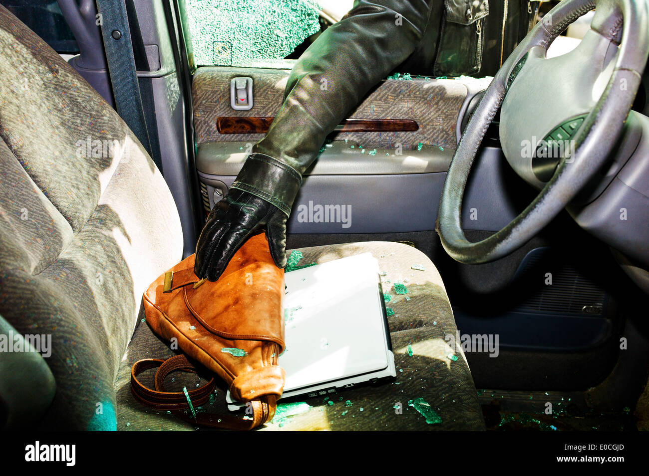 A thief steals a handbag from a car by a broken side window Stock Photo