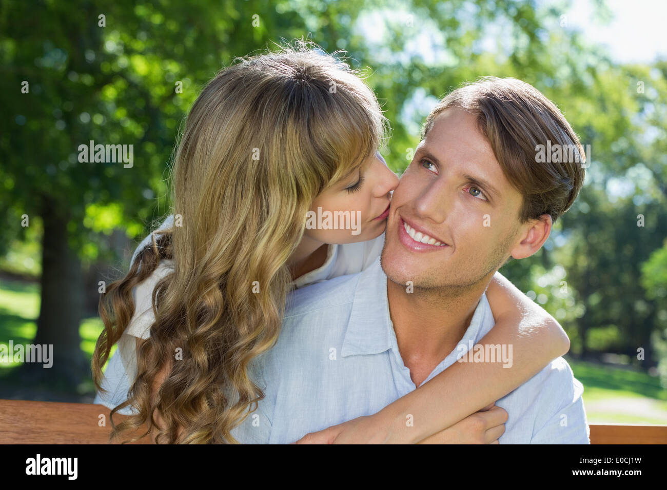 Affectionate couple relaxing on park bench together Stock Photo