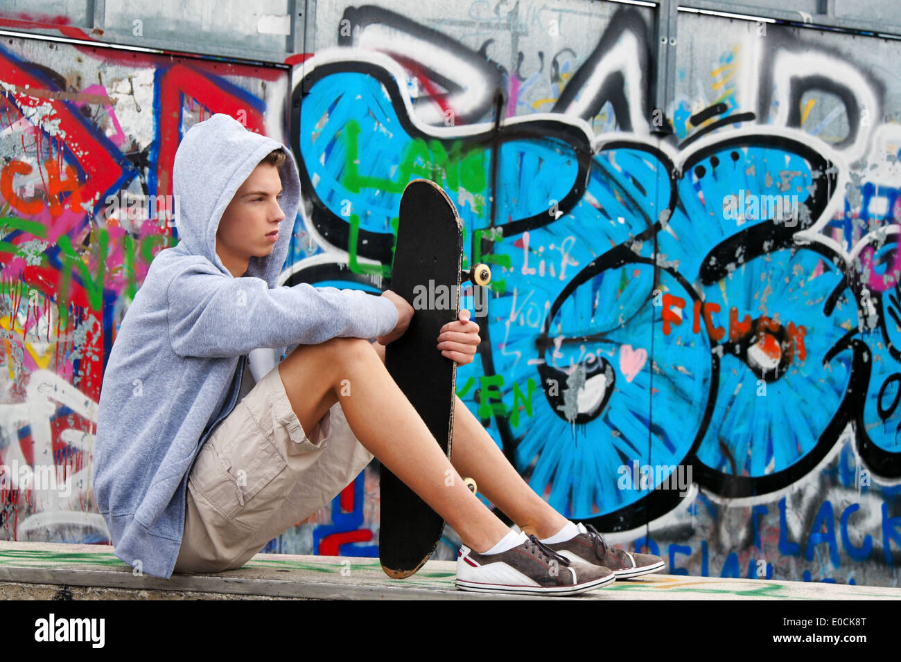 A cool looking youthful man infront of graffiti, Ein cool blickender Jugendlicher Mann vor Graffiti Stock Photo