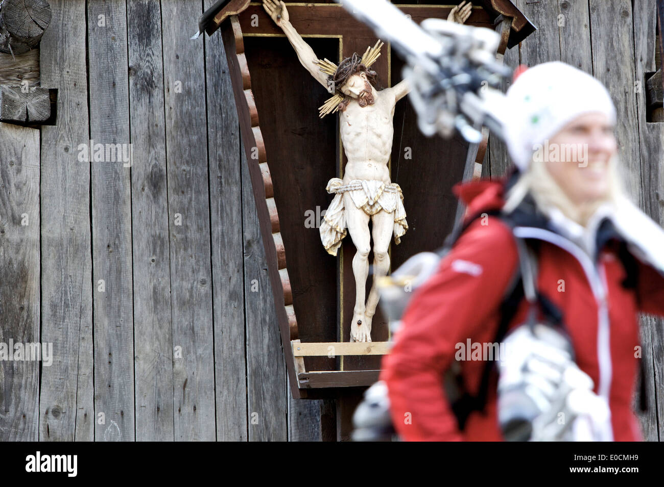 Young female skier walking past a wayside cross, See, Tyrol, Austria Stock Photo