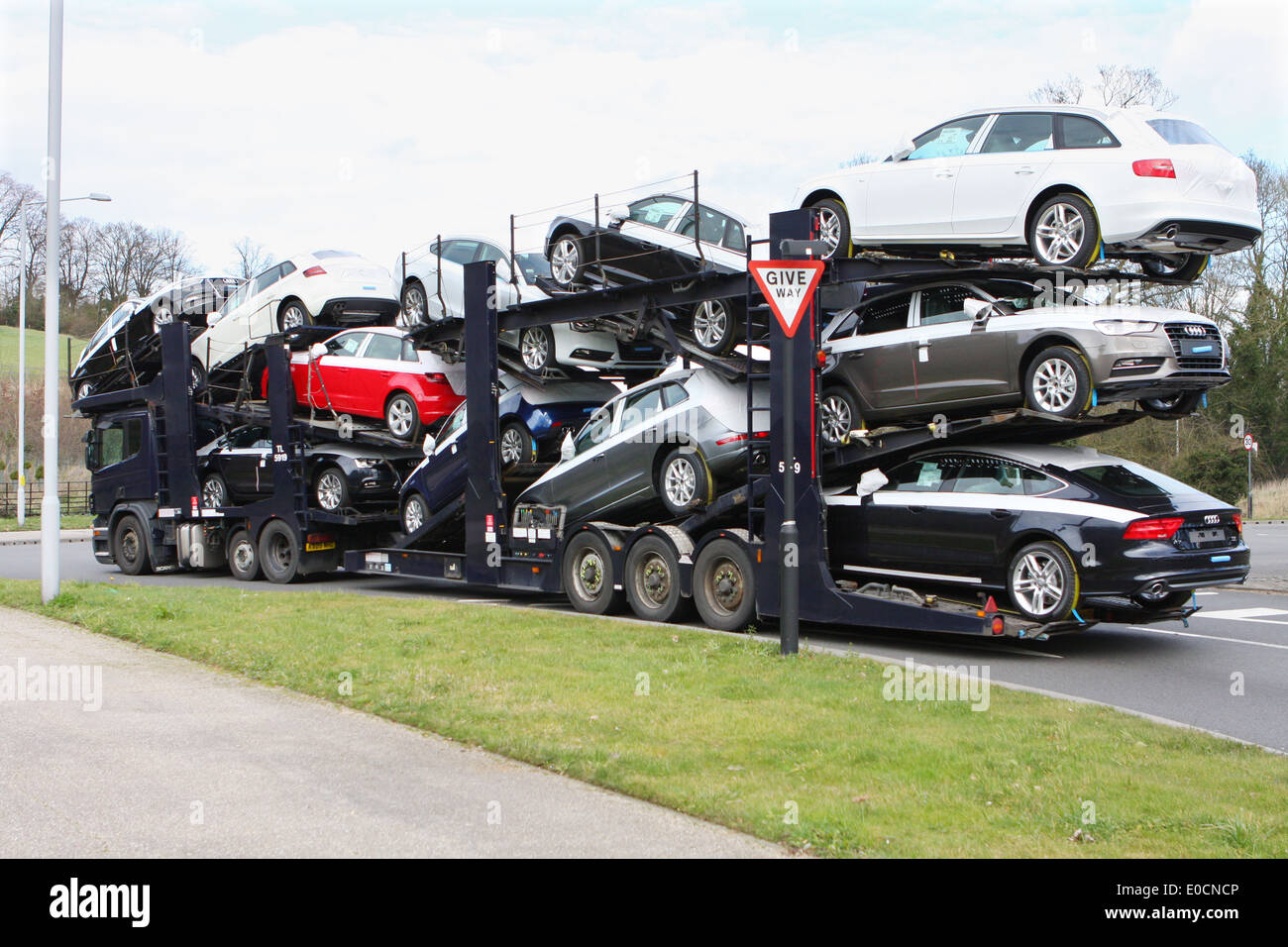 A car transporter carrying a load of new Audi cars and traveling around a roundabout in Coulsdon, Surrey, England Stock Photo