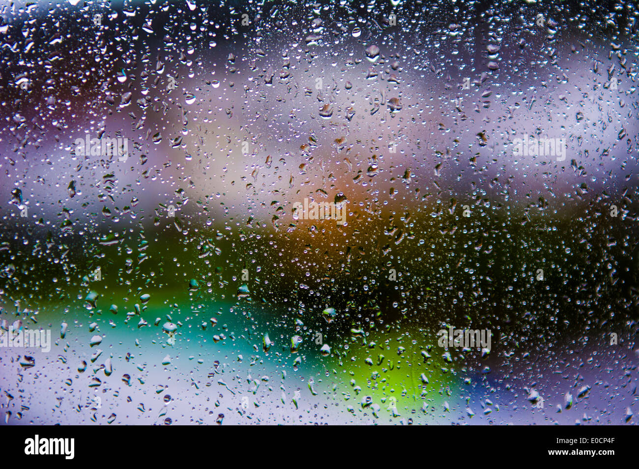 Rainwater droplets on a glass window pain with the background out of focus. Stock Photo