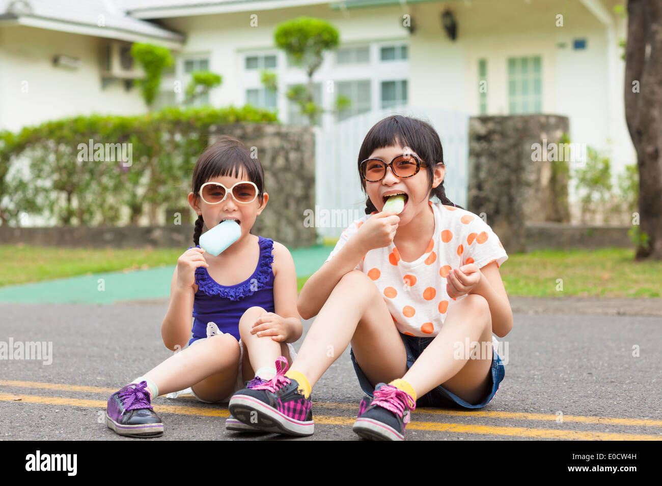 little Girls Eating Ice Cream and sitting before their house Stock Photo