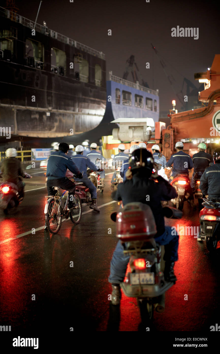 Workers on mopeds during shift change at night, Hyundai Heavy Industries (HHI) dockyard, Ulsan, South Korea Stock Photo