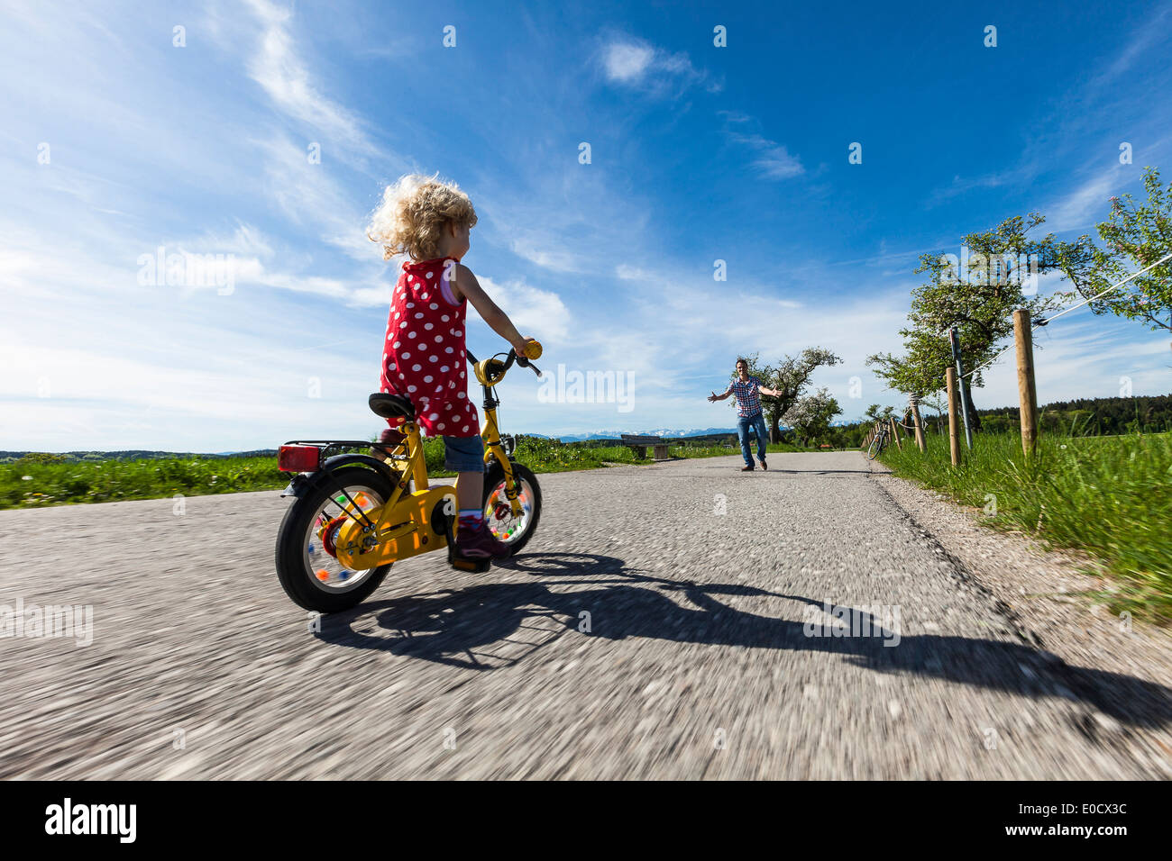 Girl cycling, father in background, Upper Bavaria, Germany Stock Photo