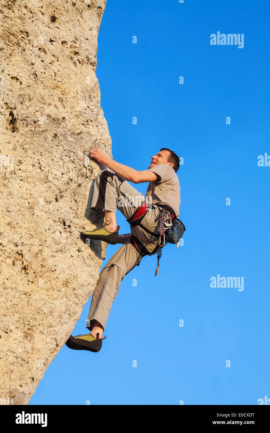 Extreme rock climbing, man on natural wall with blue sky. Stock Photo