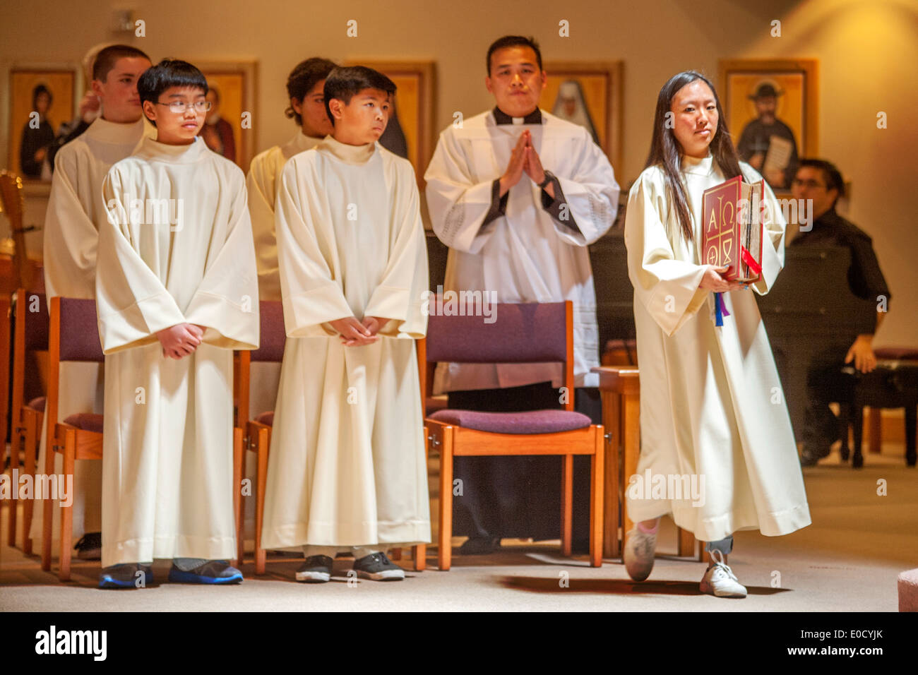 Young robed altar servers participate in Holy Thursday mass at St. Timothy's Catholic Church, Laguna Niguel, CA. Note Bible and Vietnamese assistant pastor. Stock Photo