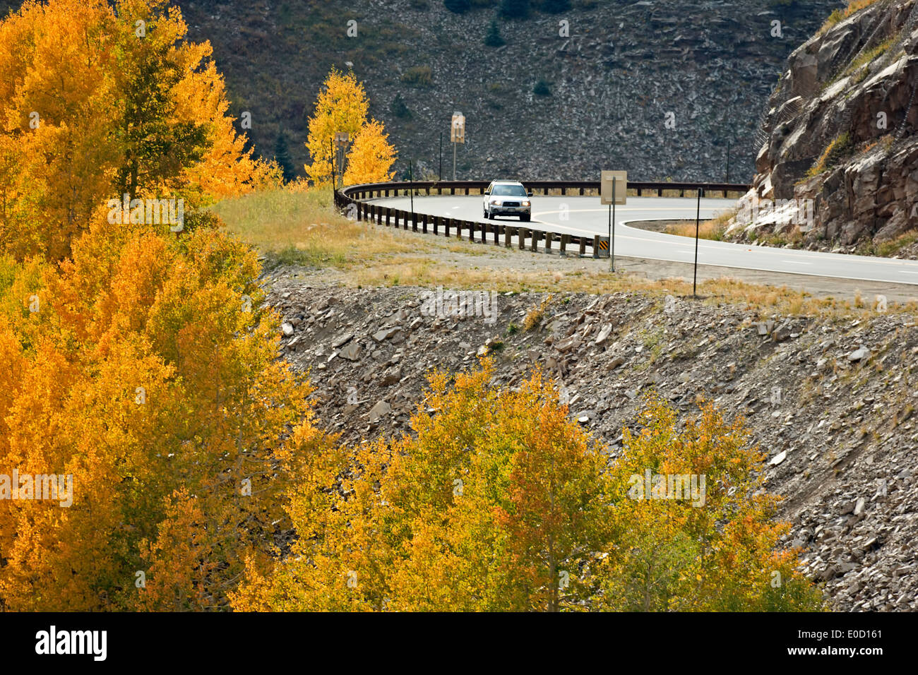 Car on Million Dollar Highway (US 550) and aspens in fall colors, near Molas Pass, San Juan Mountains, Colorado USA Stock Photo