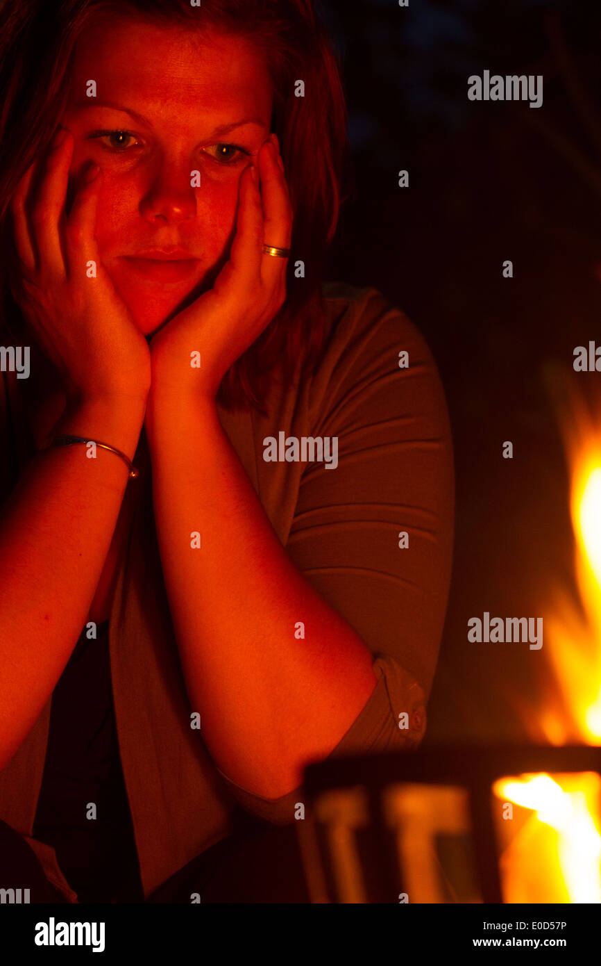 Female is staring into the fire Stock Photo