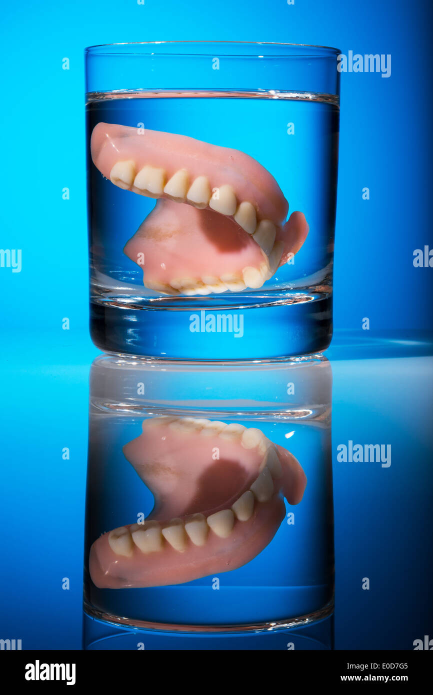 A set of dentures is cleaned in a glass with water. Right hygiene., Ein Zahnersatz wird in einem Glas mit Wasser gereinigt. Rich Stock Photo