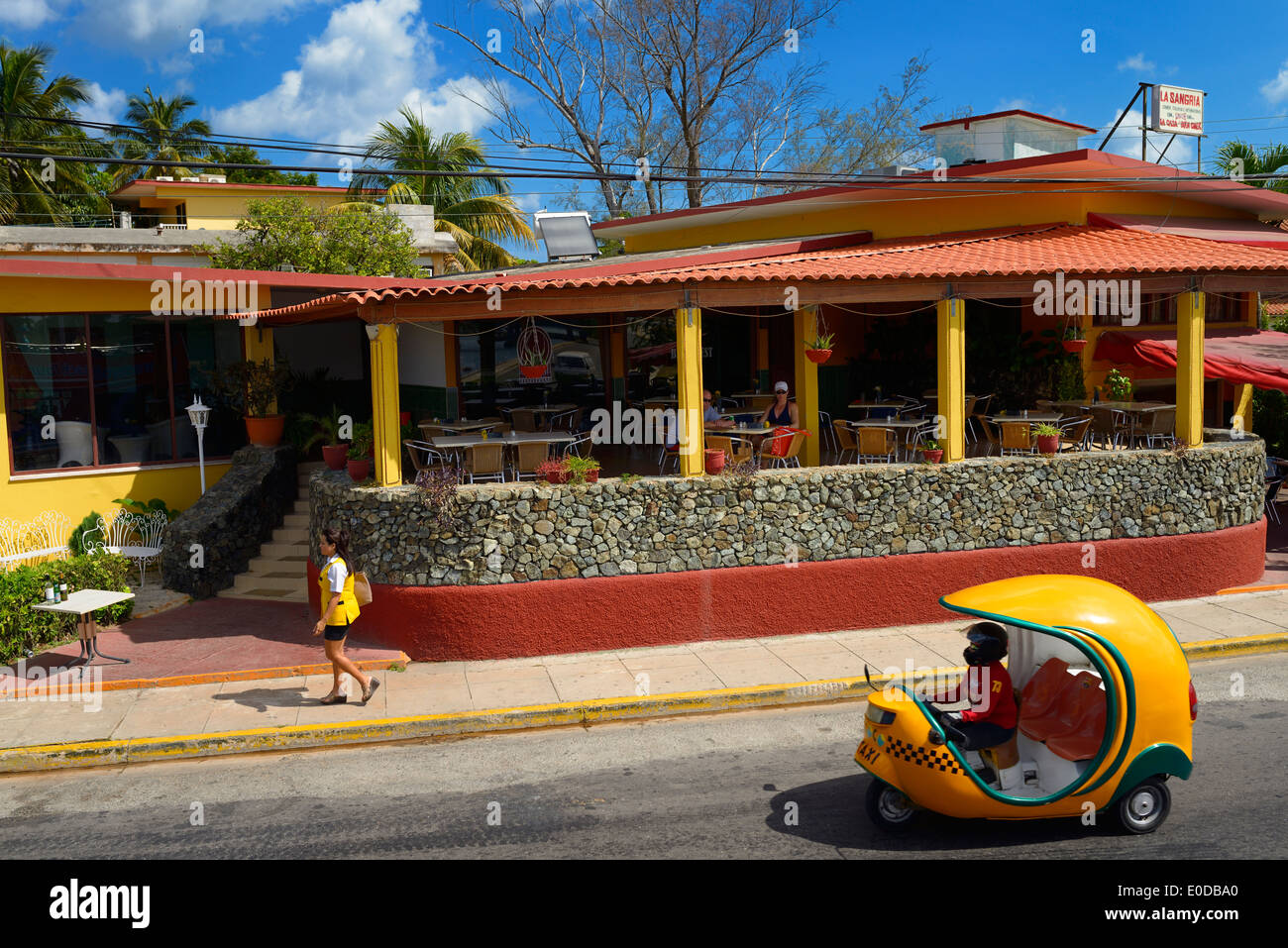 Couple at a cafe in Varadero Cuba with Coco motor bike auto rickshaw taxi Stock Photo