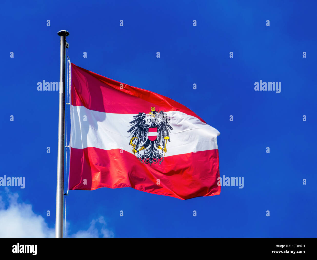 The Austrian flag blows in the wind before blue sky. Flag Austria, Die oesterreichische Fahne weht im Wind vor blauem Himmel. Fl Stock Photo