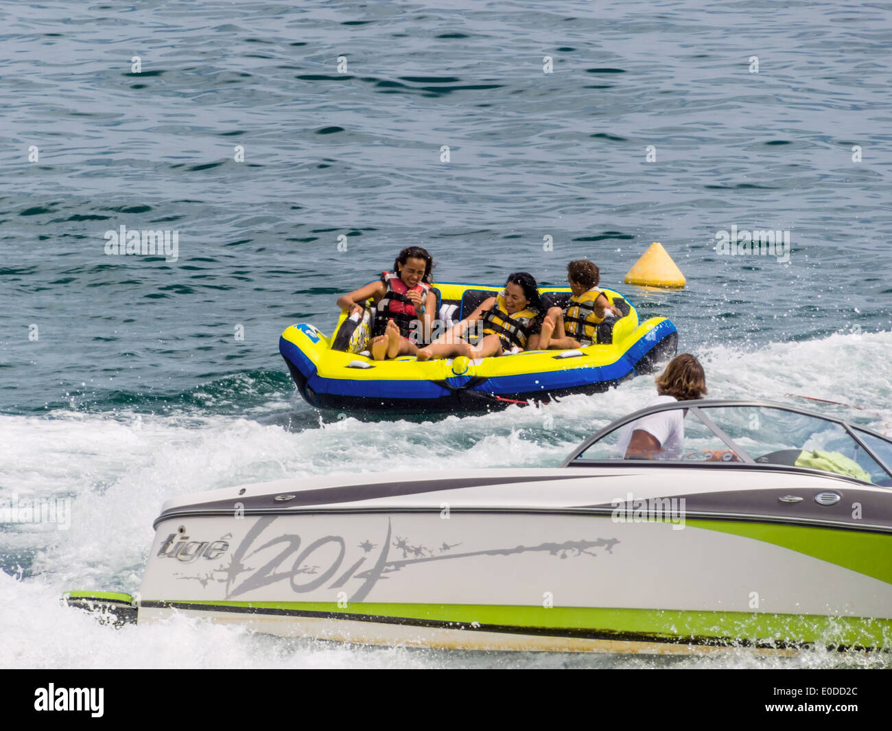 Vacationers in a rubber dinghy in the surf are pulled by motorboat., Urlauber in einem Schlauchboot in der Brandung werden von M Stock Photo