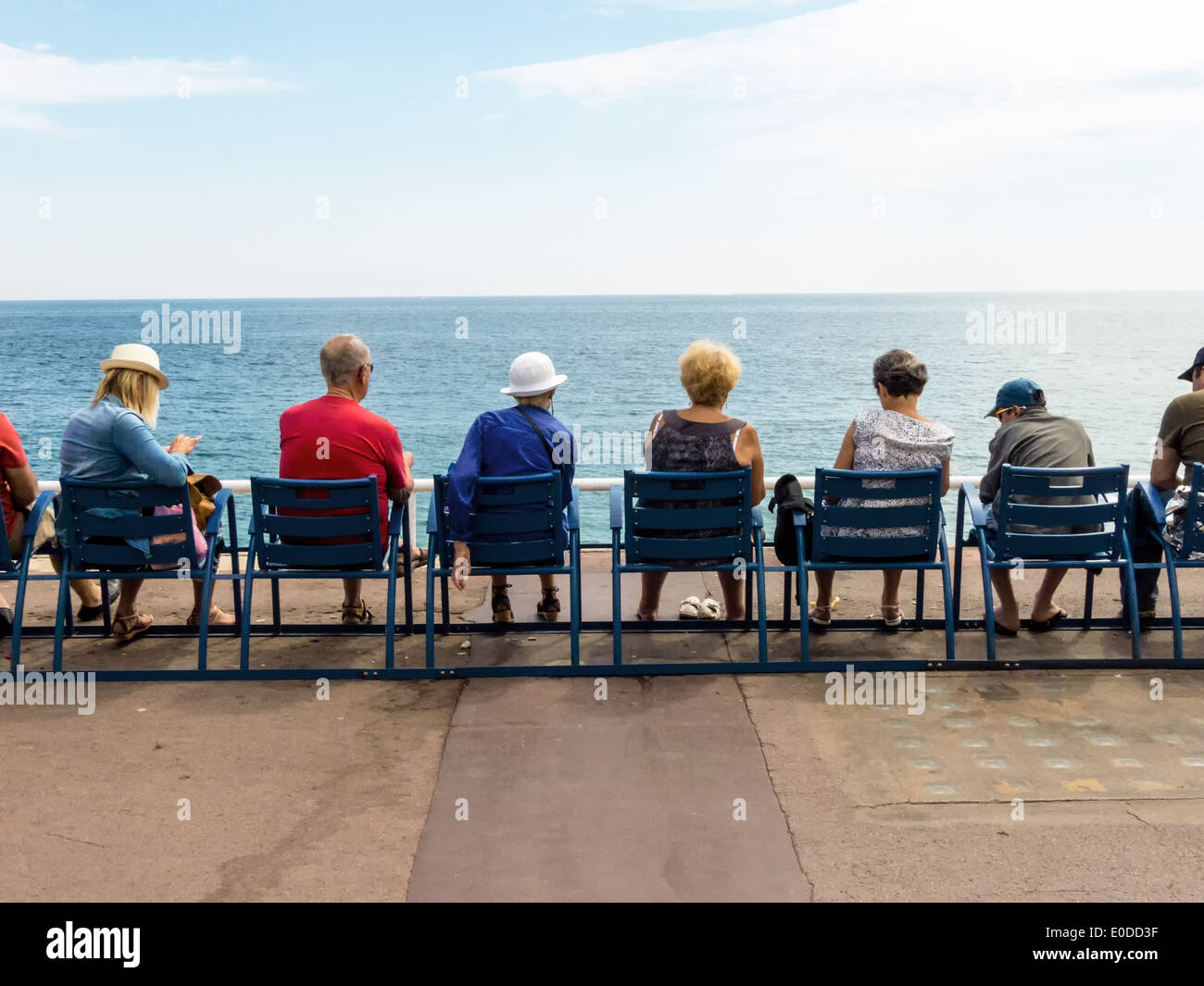 Vacationers sit in a row and look at the sea, Urlauber sitzen in einer Reihe und blicken aufs Meer Stock Photo