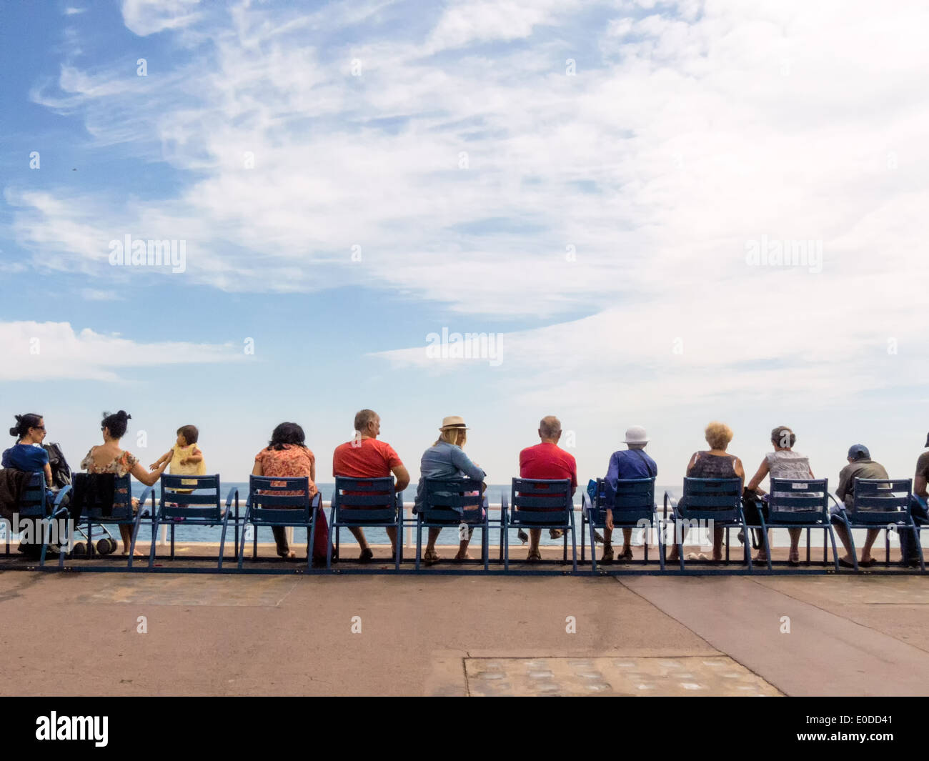 Vacationers sit in a row and look at the sea, Urlauber sitzen in einer Reihe und blicken aufs Meer Stock Photo
