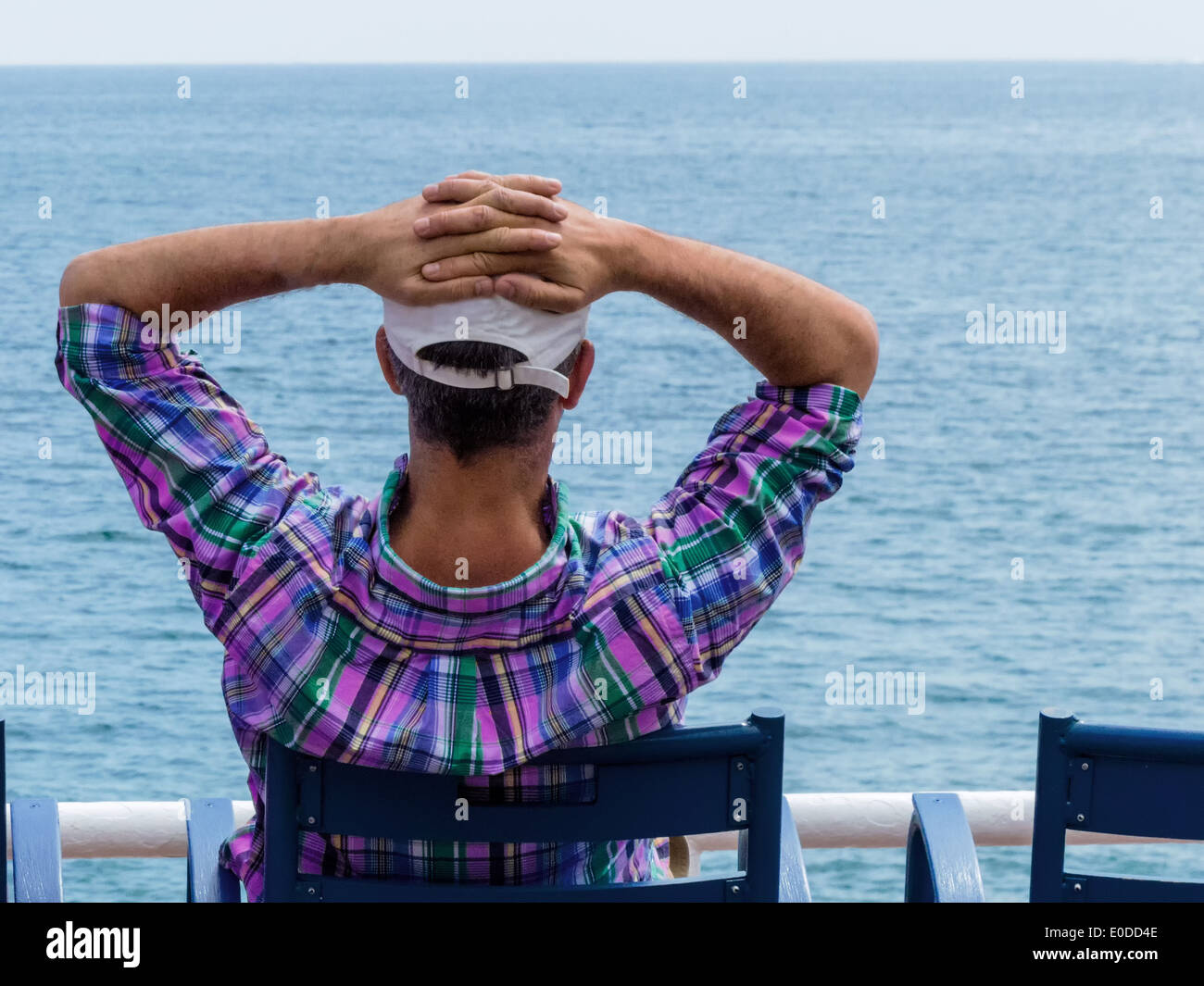 Vacationer sits on a chair and looks at the sea, Urlauber sitzt auf einem Stuhl und blickt aufs Meer Stock Photo