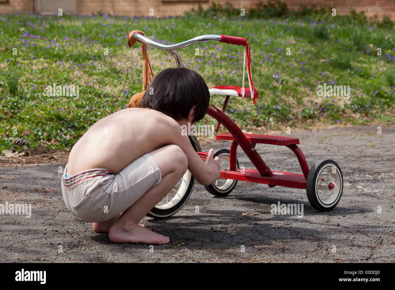 Child repairing tricycle Stock Photo