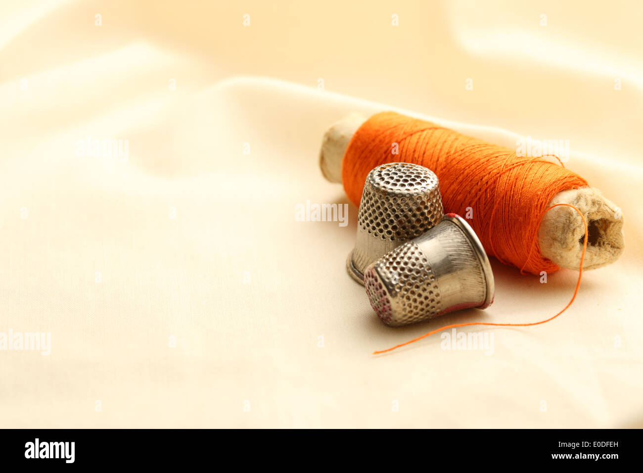Sewing thimbles, bobbin and needle on silk cloth Stock Photo Alamy