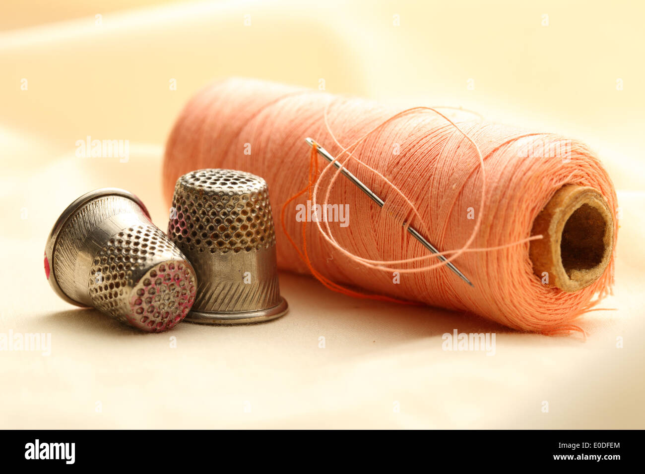 Sewing thimbles, bobbin and needle on silk cloth Stock Photo Alamy