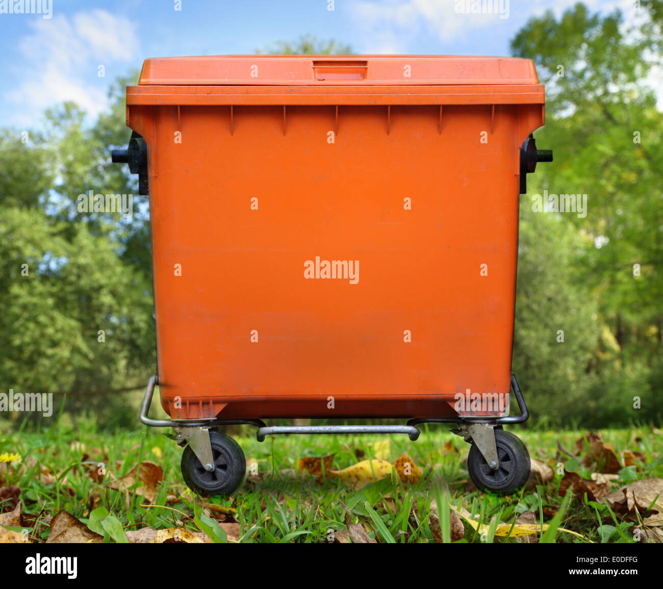 Orange garbage bin on foliage Stock Photo Alamy