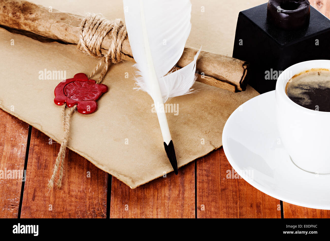 cup of coffee with a quill pen and inkwell parchment scroll on wooden background Stock Photo
