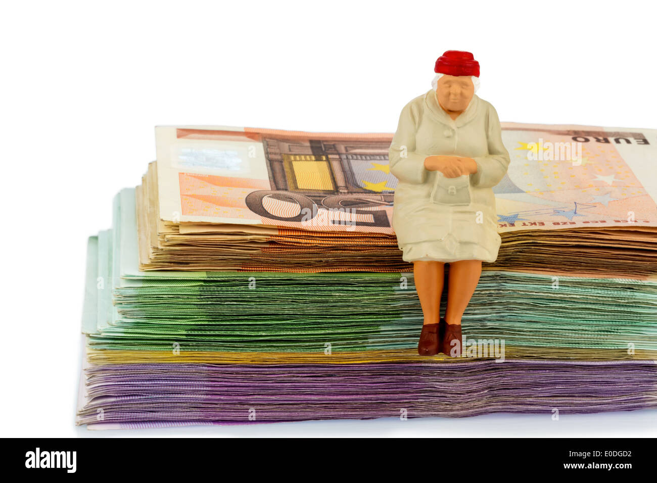 Figure of an old woman sits on a pile of bank notes, symbolic photo for pension scheme and rest state, Figur einer alten Frau si Stock Photo