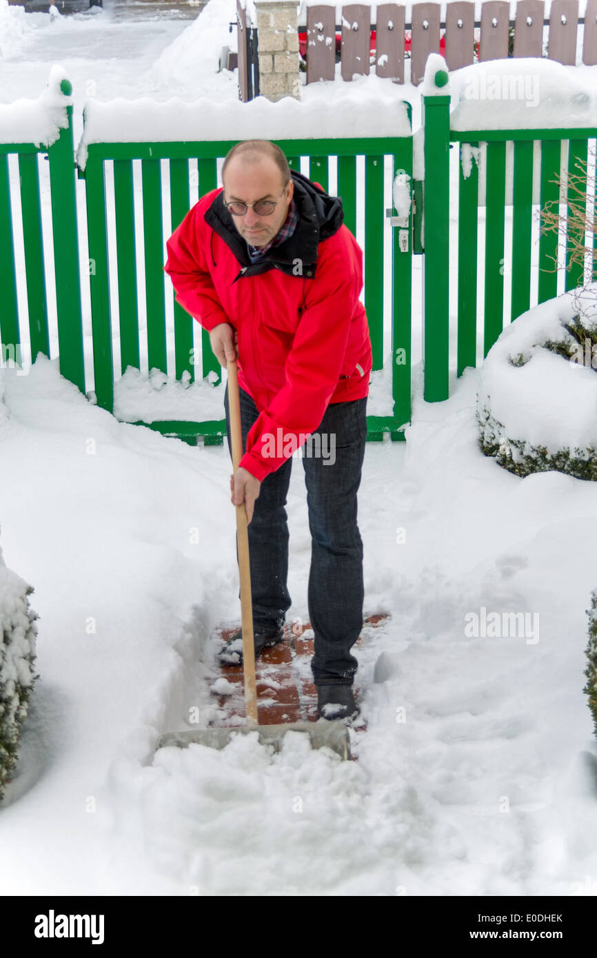 Snow is shoveled by a house away. Snowy clearing in winter, Schnee wird von einem Haus weg geschaufelt. Schneeraeumung im Winter Stock Photo