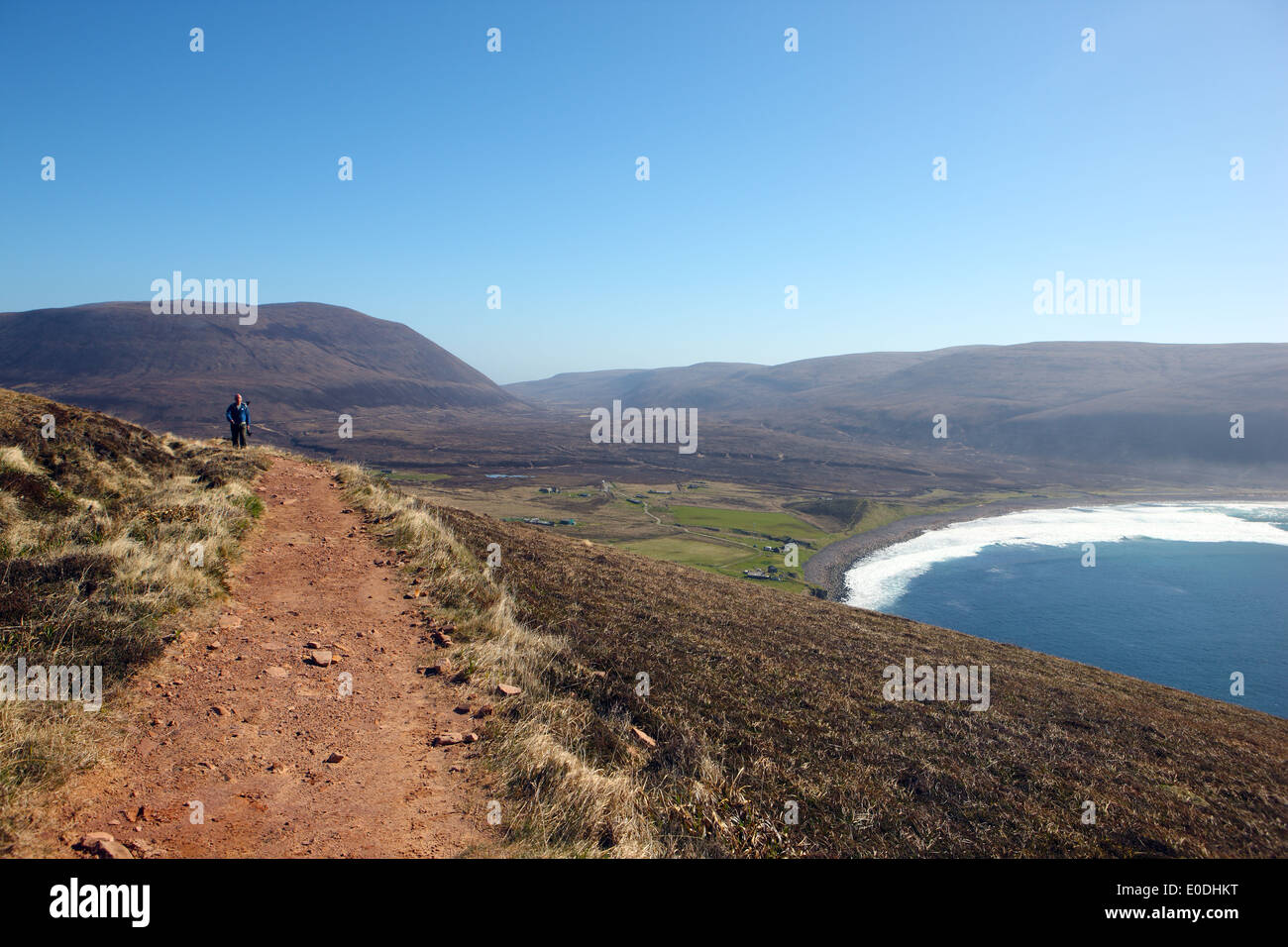 Walker on the path to the Old Man Of Hoy, in Orkney, with the village and Bay of Rackwick on the low land beyond Stock Photo