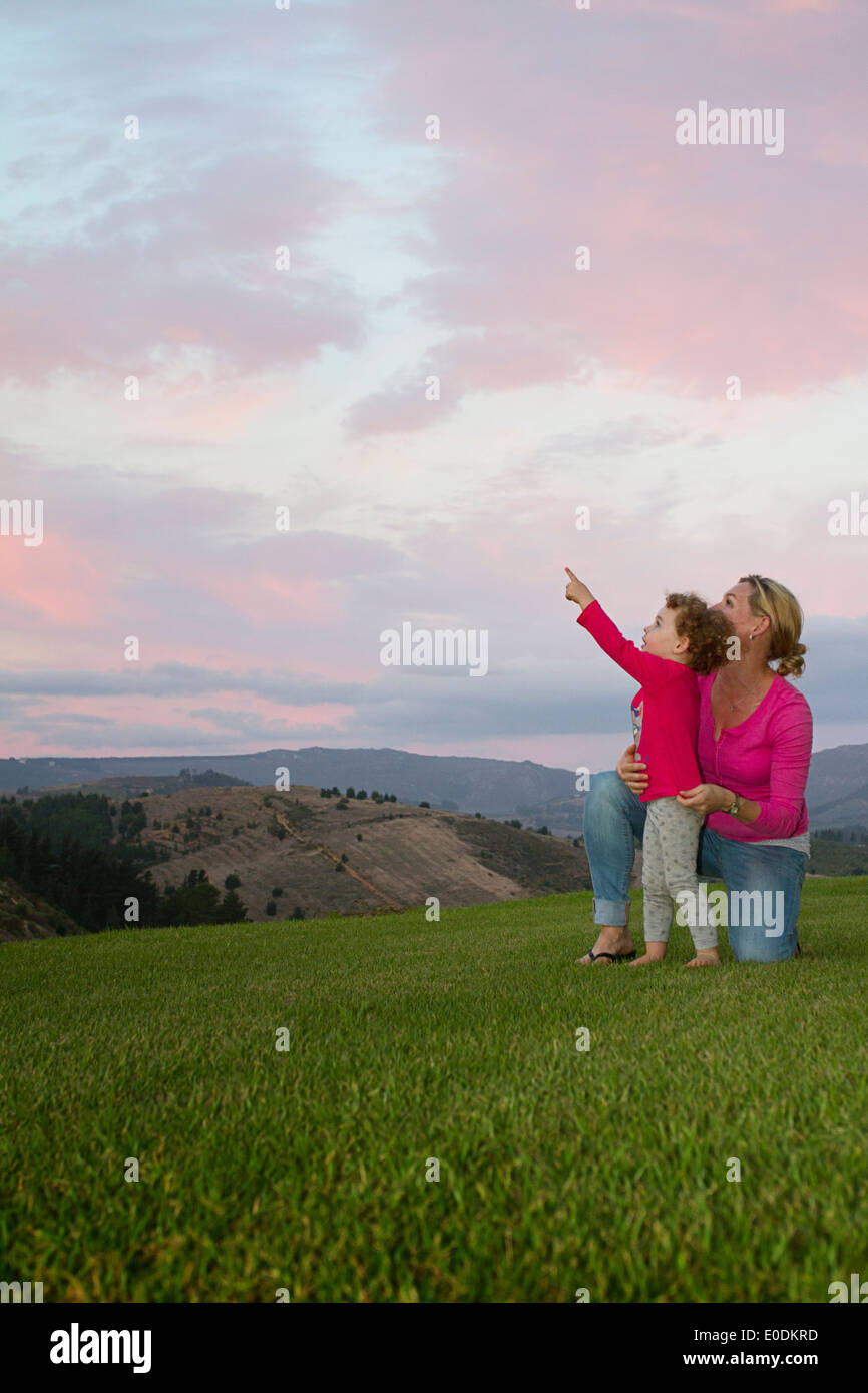 Mom and daughter pointing to the sky at sunset Stock Photo - Alamy