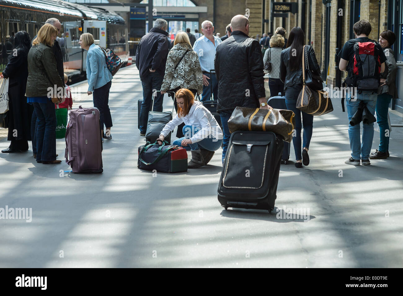 A young woman checks her bag after alighting from a train at Kings Cross Station London England Britain British English rail UK Stock Photo